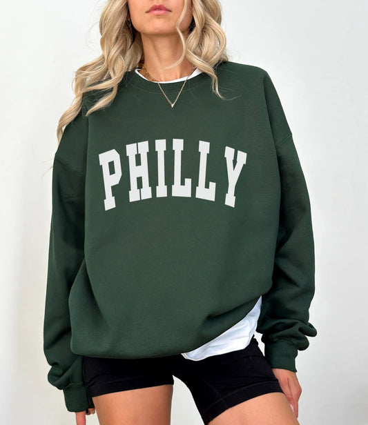 Person wearing a green sweatshirt with 'PHILLY' printed on it against a white background