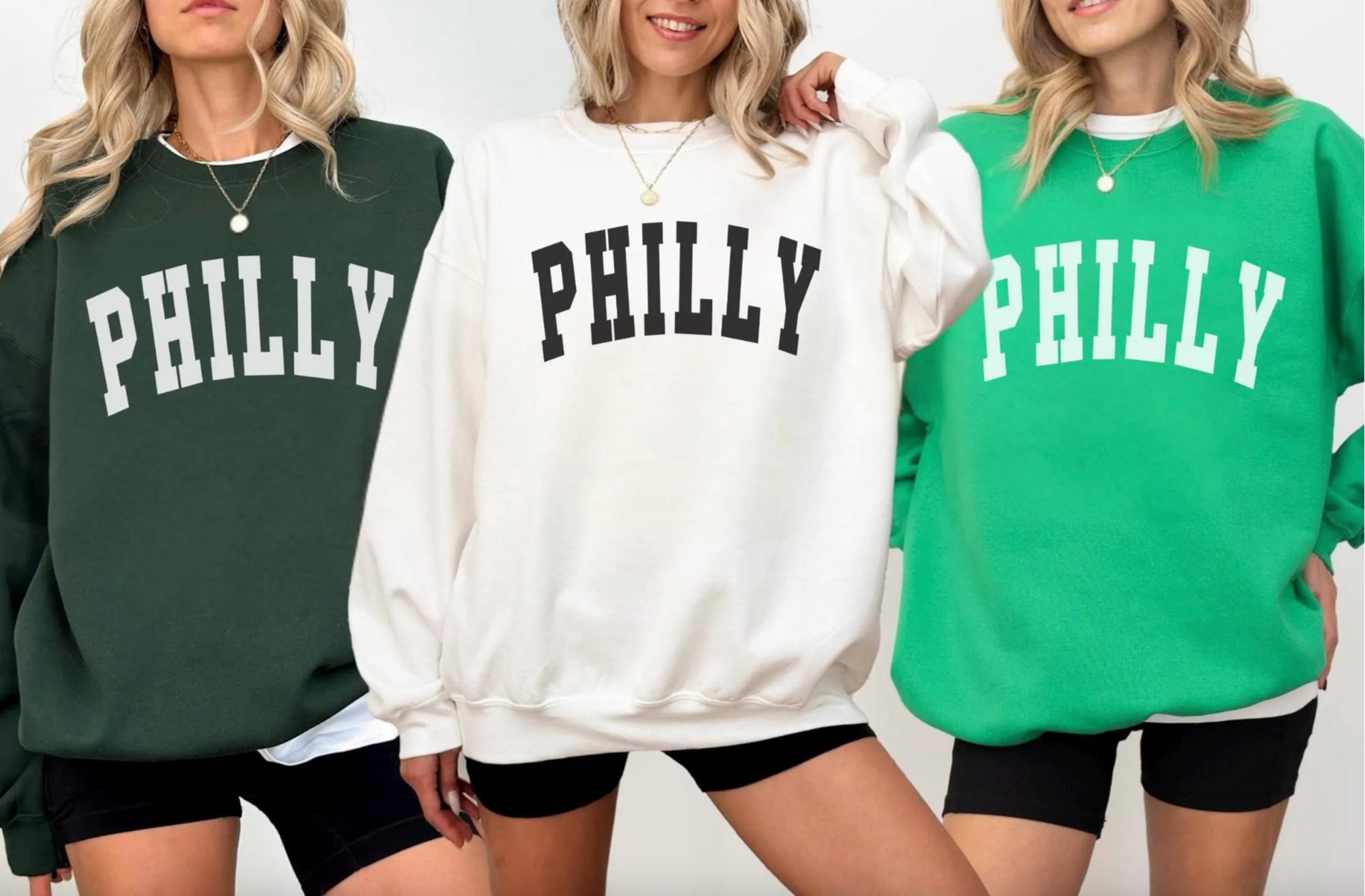 Three women wearing sweatshirts with 'PHILLY' printed on them.